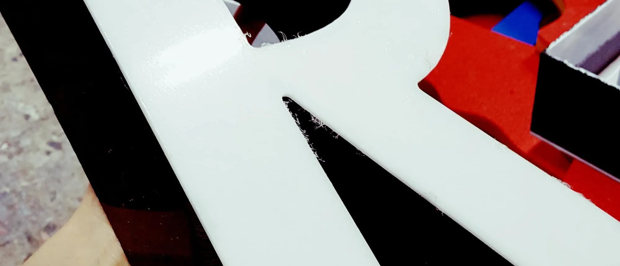 A fabricated white dimensional letter held up in a signage workshop