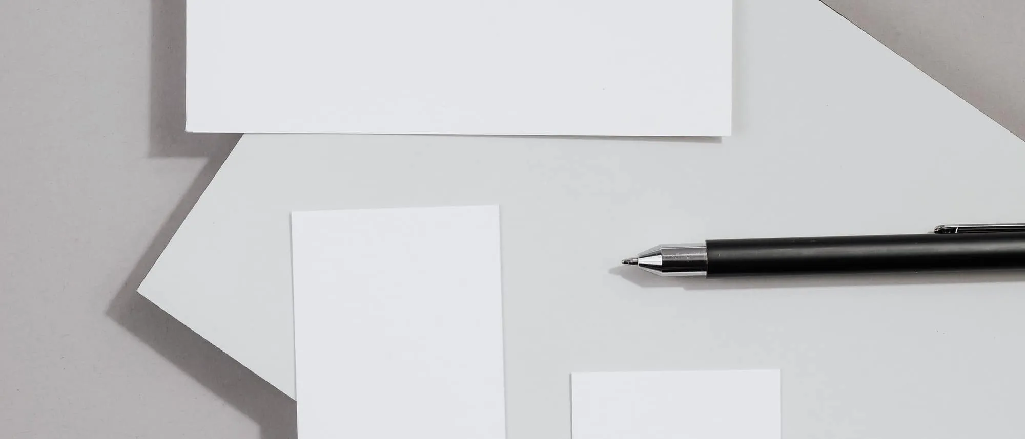 A stack of blank business cards and a pen photographed from above
