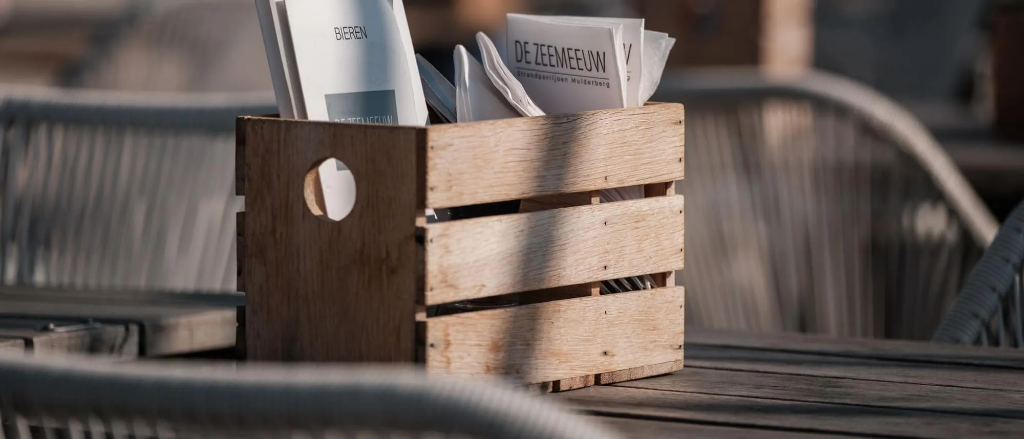 A sunlit café terrace where printed material is handed out