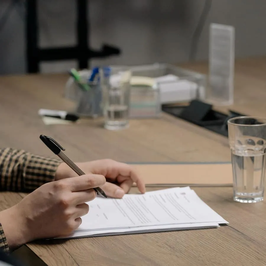 A person signing off printed documents at a desk