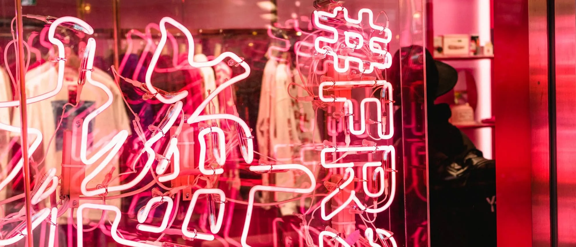 Pink neon lettering glowing in a shop window at night
