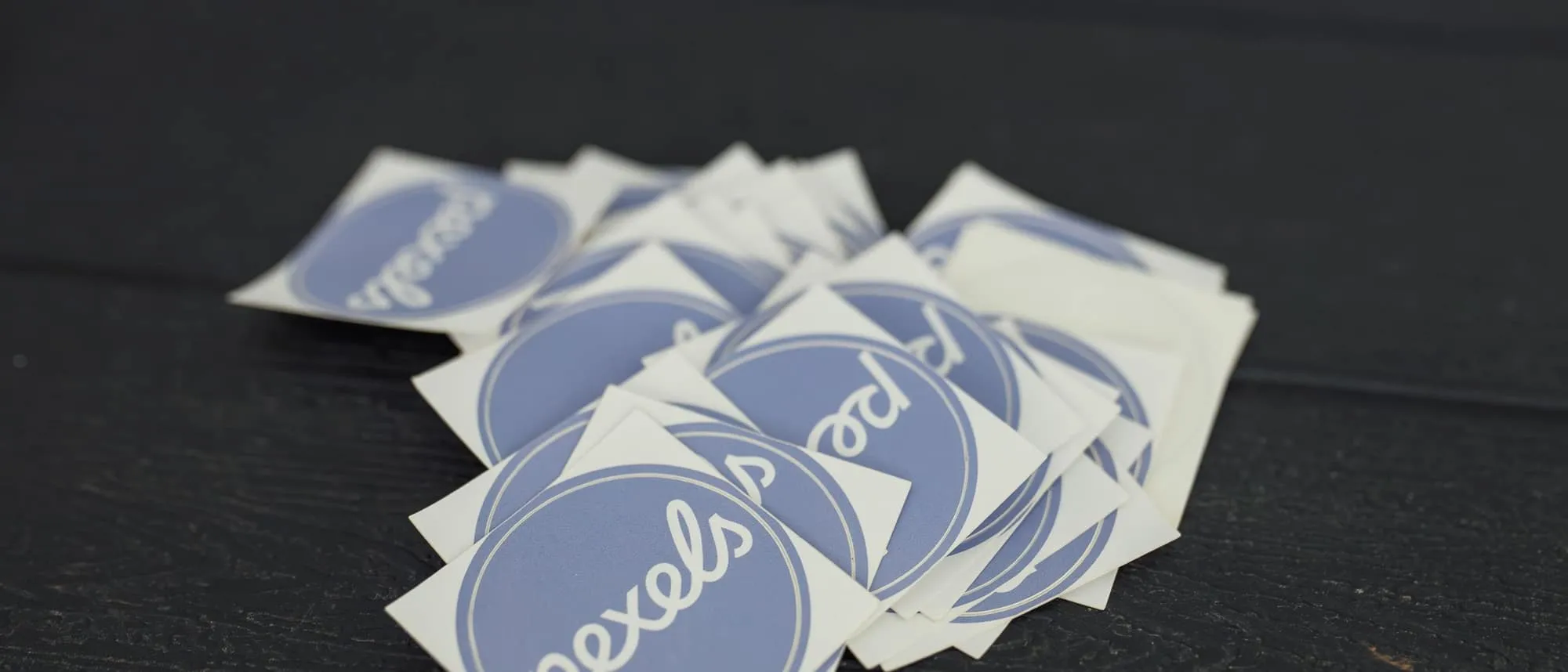 A stack of die-cut printed stickers on a dark wooden surface