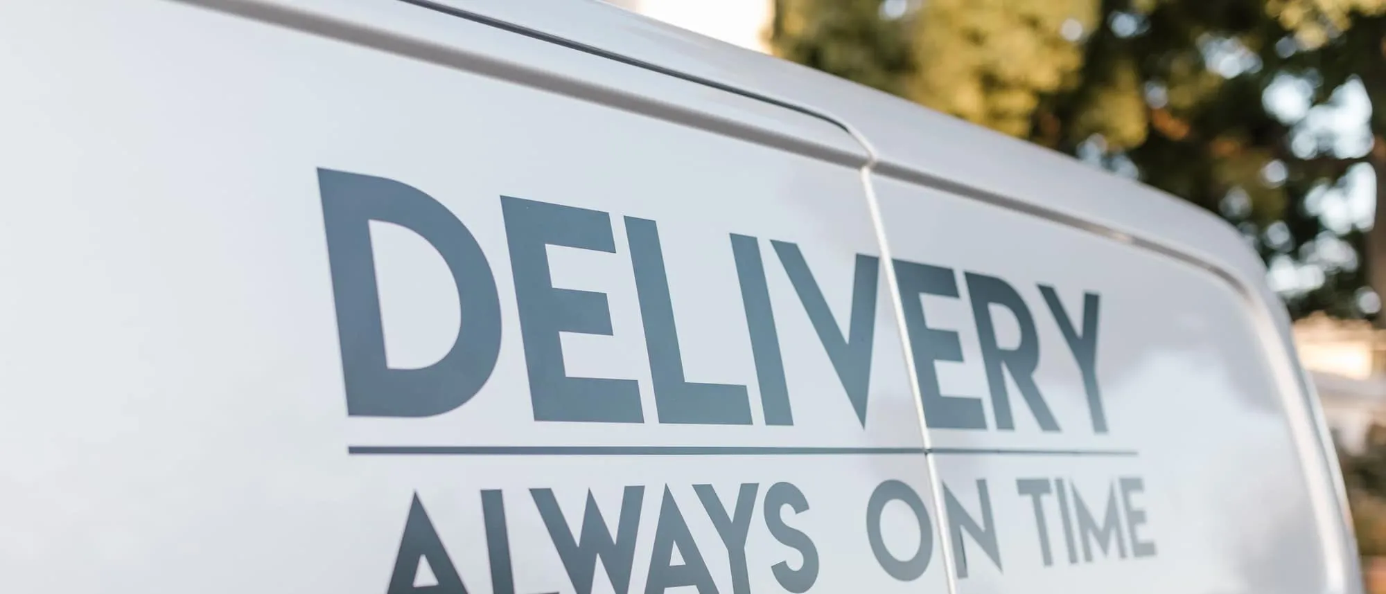 A delivery van carrying printed vinyl branding on its side panel