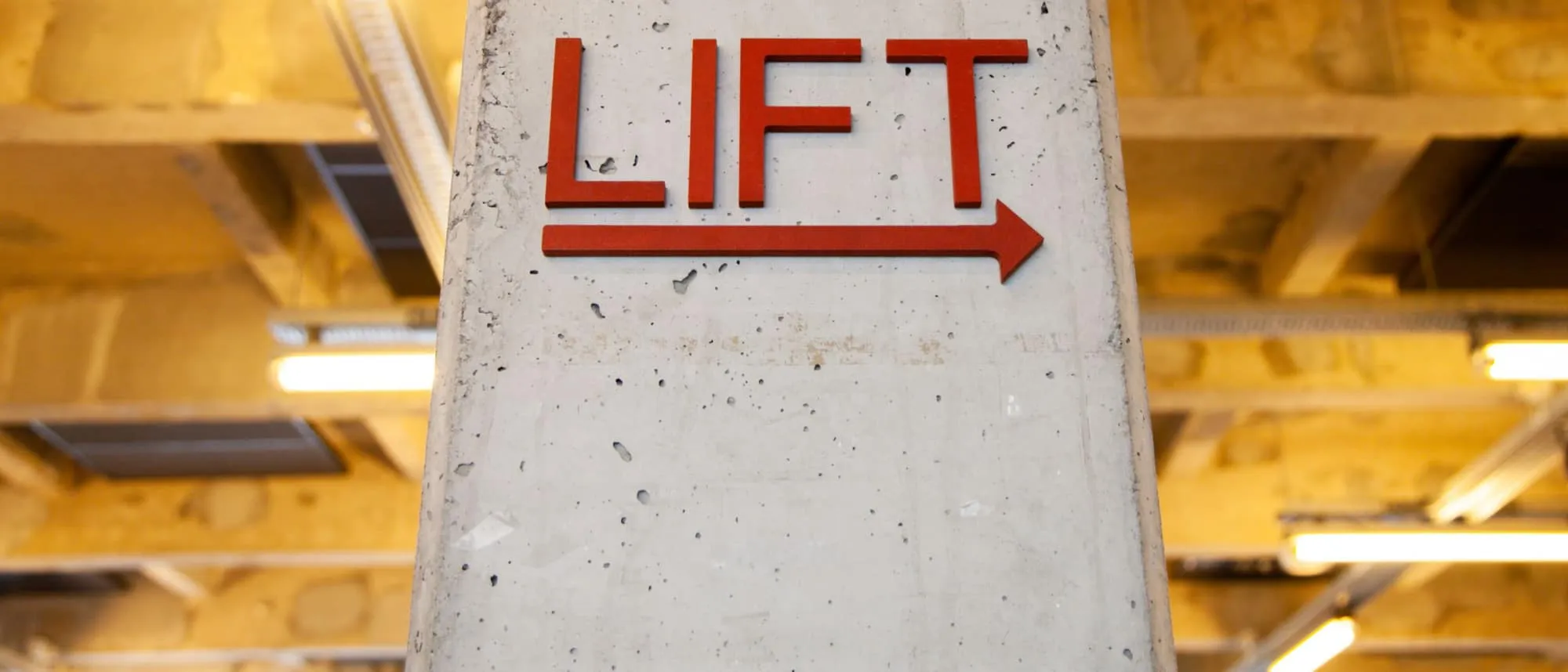 A directional sign reading LIFT with an arrow on a concrete column