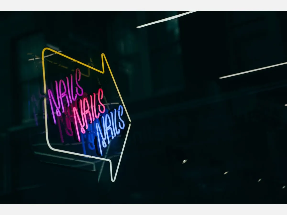 A neon arrow sign glowing above a salon entrance at night