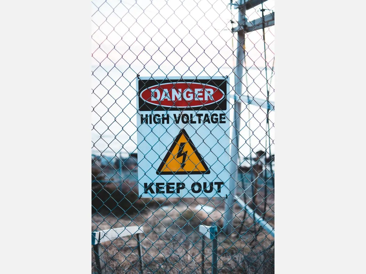 A danger warning sign fixed to a site perimeter fence